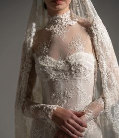 a woman in a wedding dress with a veil over her head and hands on her hips