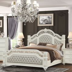 a white bed sitting in a bedroom next to a chandelier