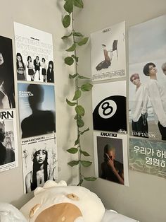 a bedroom with posters on the wall and a plant growing in the corner next to it