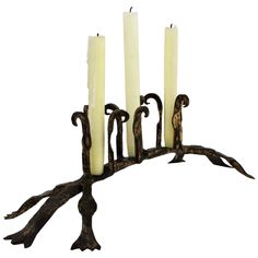 an iron candelabra with five lit candles on it and branches in the middle