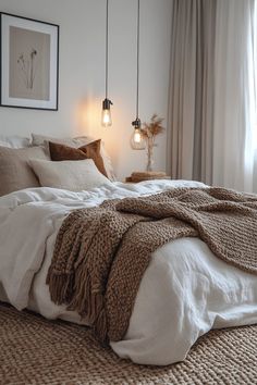 a bed with two lamps hanging above it and a blanket on the floor next to it