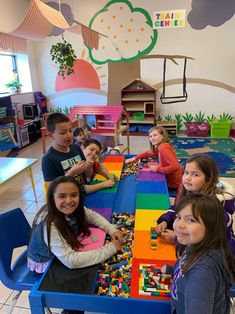 a group of children sitting at a table with legos on it