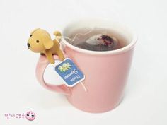 a pink coffee mug filled with hot chocolate and a dog figurine