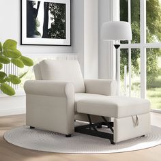 a living room with a white chair and large window in the back ground, next to a rug that has a plant on it