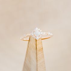 a white diamond ring sitting on top of a wooden stand