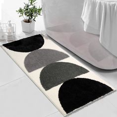 a white rug with black and grey circles on it next to a bathtub in a bathroom