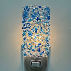 a light that is on the side of a wall with blue and white glass pieces