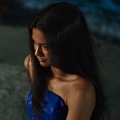 a woman in a blue dress looking at her cell phone