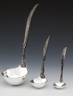 three spoons and two bowls with handles in the shape of fish tails, on a gray background