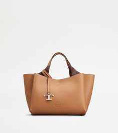 Bag in soft exposed grain leather, with Tod's logo stamped on the front, flat handles and removable shoulder strap. The interior comes with three compartments separated by zipped central pockets. An elegant creation enhanced by distinctive iconic detailing, such as the metal T Timeless pendant and T-stitching. Tan Satchel With Double Handle, Crossbody Bag With Leather Handles In Pebbled Leather, Crossbody Bag With Pebbled Leather And Leather Handles, Soft Pebbled Leather Bag With Top Handle, Soft Pebbled Leather Top Handle Bag, Pebbled Leather Tote Bag With Removable Pouch, Tan Leather Shoulder Bag With Handle Drop, Cognac Calf Leather Tote Bag, Tan Pebbled Leather Bag For Everyday Use