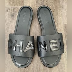 Chanel 2023 Black Leather Slides Size 37 It= 6.5 Us New In Box With Dust Bag Sold Out Everywhere Luxury Black Flat Heel Sandals, Black Flat Heel Calf Leather Sandals, Designer Black Slides With Cushioned Footbed, Luxury Black Flat Slides, Chanel Leather Slides, Luxury Black Cushioned Slides, Chanel Puffy Sandals, Black Flat Leather Shoes, Chanel Slides