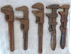 five old rusty wrenches are lined up on a white cloth