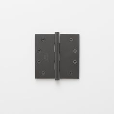 two black metal door hinges on a white wall