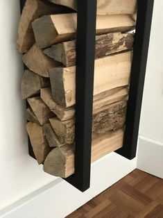 a stack of wood sitting on top of a wooden floor next to a white wall