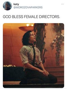 a man sitting on the ground in front of a wall with words that read, god bless female directors