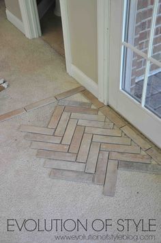 the floor is being laid out in front of an open door and there are some pieces of tile on the ground