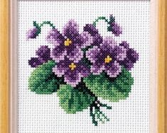 a cross stitch picture of purple flowers on a white background