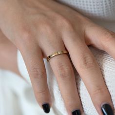 a woman's hand with black fingernails and gold ring