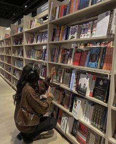 a woman kneeling down in front of a bookshelf filled with lots of books