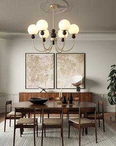 a dining room table and chairs with two paintings on the wall