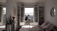 a woman is sitting at the window in her bedroom