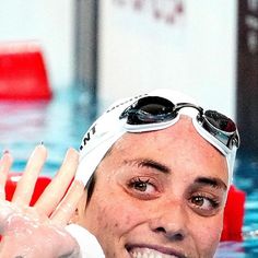 a man with goggles on his head and swimming in a pool smiling at the camera