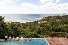 some people are sitting in the pool looking out at the water and trees on the other side