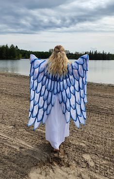 a woman walking on the beach with an angel wings costume over her shoulder and back