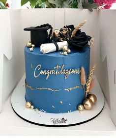 there is a blue cake with gold decorations on the top and congratulations written on it