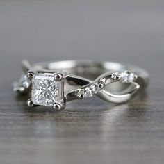 a white gold engagement ring with a princess cut diamond in the center and side stones on each band