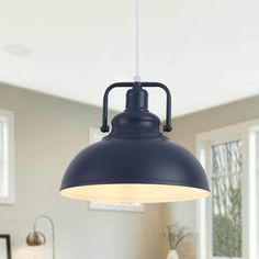 an industrial style pendant light hanging over a kitchen island table in a home with white walls and hardwood flooring