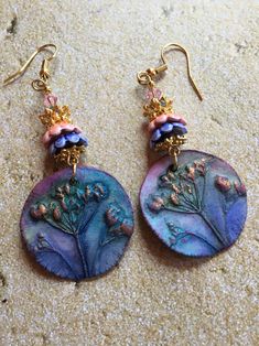 These Ceramic Earrings are made with charms made by an artisan.  The earrings are accented with ceramic and metal flower bead caps and Swarovski crystals Nature-inspired Drop Flower Earrings For Pierced Ears, Nature-inspired Multicolor Dangle Jewelry, Artistic Purple Jewelry With Matching Earrings, Artisan Flower Earrings For Pierced Ears As Gift, Handmade Artistic Flower Earrings, Handmade Pendant Earrings With Adjustable Fit, Handmade Adjustable Pendant Earrings, Artistic Handmade Flower Earrings, Handmade Nature-inspired Pink Earrings