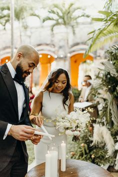 a bride and groom are cutting their wedding cake at an outdoor venue with candles in the foreground