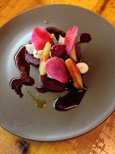 a plate topped with fruit and sauce on top of a wooden table