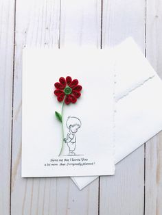 a card with a red flower on it sitting next to a piece of white paper