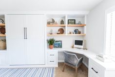 a home office with built - in shelving and desks, including a computer