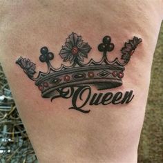 a woman's thigh with a crown tattoo on it that says queen in black ink