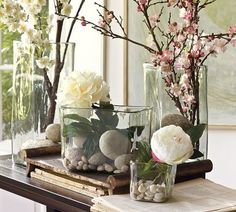 vases filled with flowers and rocks are sitting on a table next to each other