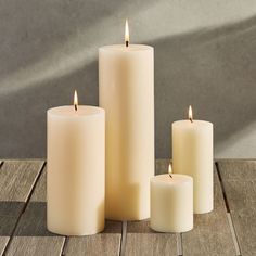 three white candles sitting on top of a wooden table