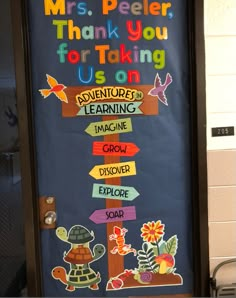 a classroom door decorated with colorful signs and flowers