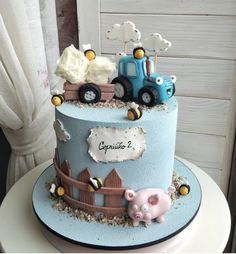 there is a blue cake decorated with farm animals and tractors on the top of it