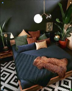 a bed with lots of pillows and blankets on top of it in a room that has black walls