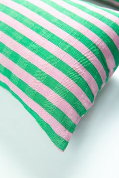 a pink and green striped pillow sitting on top of a white table