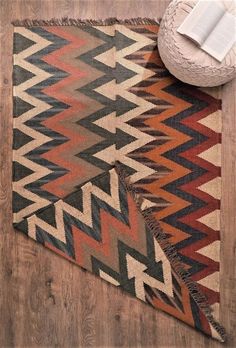 an area rug on the floor with a book and vase