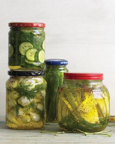 four jars filled with pickles and cucumbers