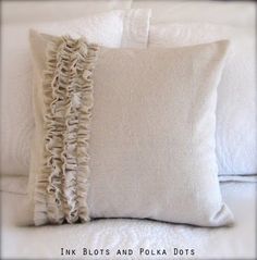 a white pillow with ruffles on it sitting on top of a bed next to pillows