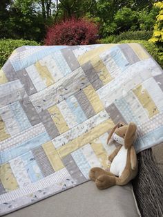 a stuffed animal sitting on top of a bed next to a quilted baby blanket