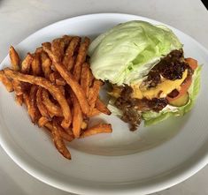 a hamburger and french fries on a white plate with a marble table in the background