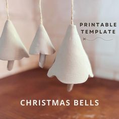 three white christmas bells hanging from strings on a wooden table with the title printable template