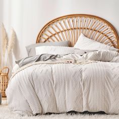 a bed with white sheets and pillows in a room next to a wicker headboard